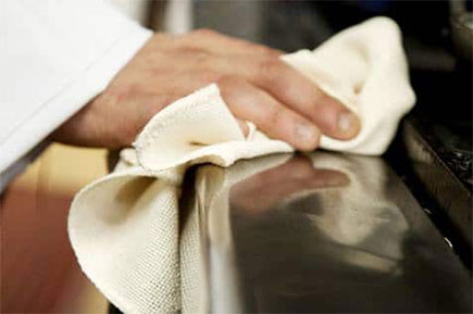 A man cleaning the kitchen using a cloth towel.